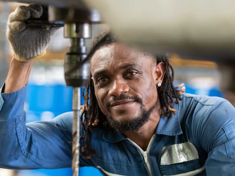 A mechanic working on a project and looking into the camera.