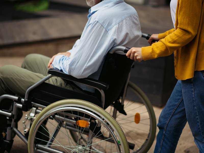 A woman pushing a man in a wheelchair.